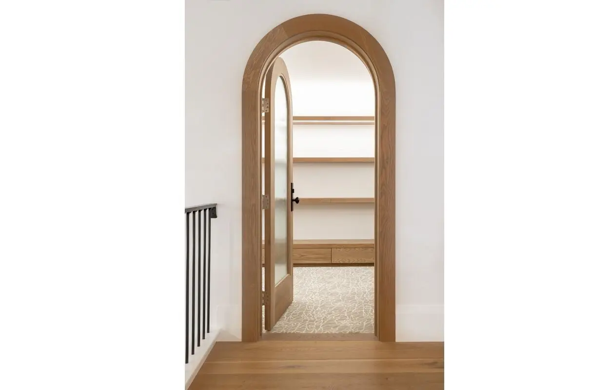 Custom arched interior door with wooden frame by Homestead Woodworks, enhancing the architectural elegance of the home